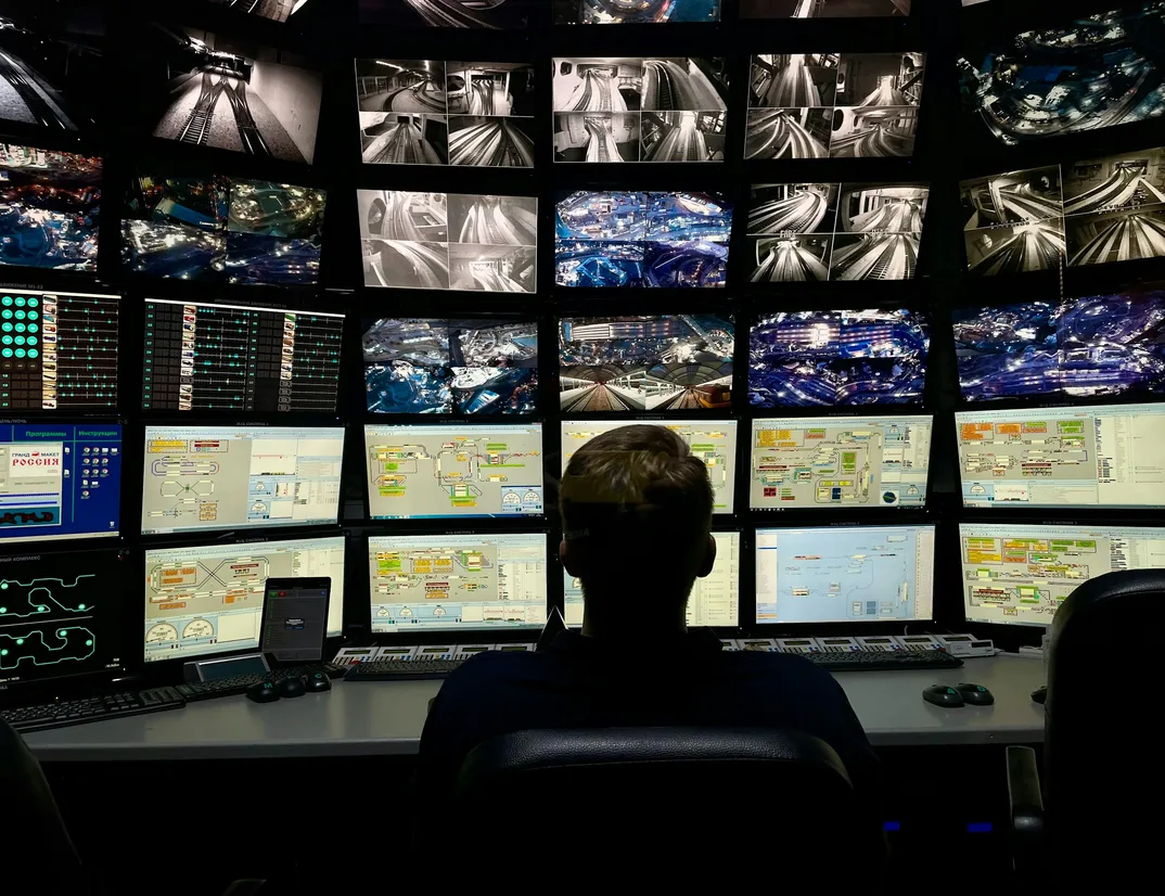 An operator watching a wall of monitoring screens in a control room