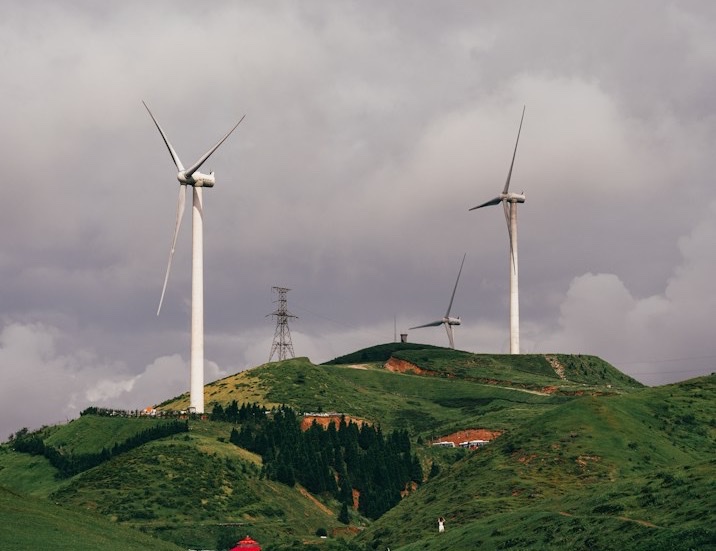 Wind turbines on a green hilltop under a cloudy sky