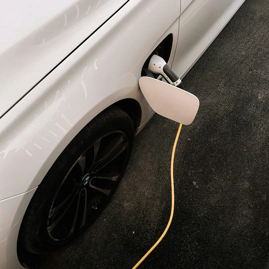 A white electric car plugged into a charging cable