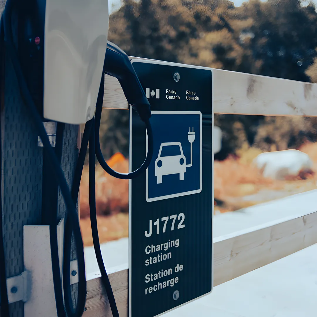 A wall-mounted EV charger beside a J1772 charging station sign